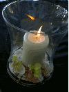 glass hurricane with pillar candle, seashells and flowers